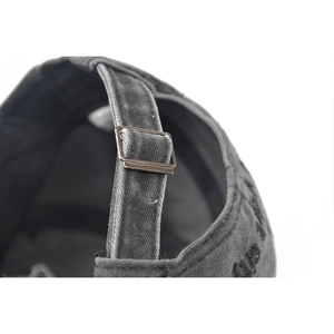 Close-up of adjustable bronze metal buckle and washed fabric texture on baseball cap