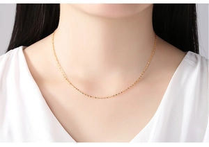 Close-up of elegant 14K gold plated thin necklace worn by a model in natural lighting