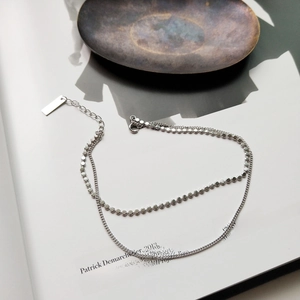 Detailed close-up of double-layered silver bead and link anklet on a magazine background