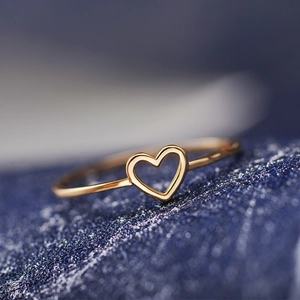 Macro detail of a minimalist thin gold band ring with a hollow heart shaped design