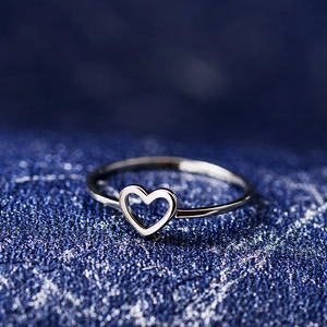 Elegant minimalist silver hollow heart ring made of silver-plated copper on blue textured background