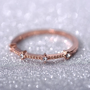 Detail of rose gold ring with three white cubic zirconia and milgrain beaded texture