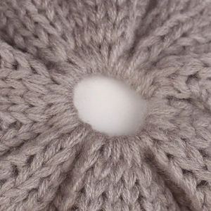 Detailed macro shot showing thick grey knit texture and radial stitching of the beanie