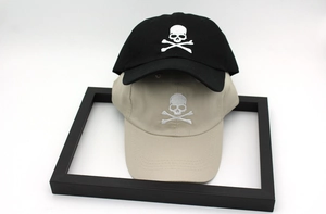 Detail of black and beige baseball caps with white skull and crossbones embroidery