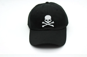 Close-up of white skull and crossbones embroidery on a black cotton baseball cap