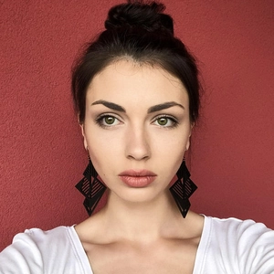 Exaggerated black geometric hollow earrings worn by model against red wall