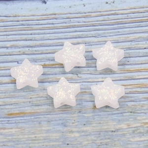 Detail of five white synthetic opal star beads with colorful luster on wood surface