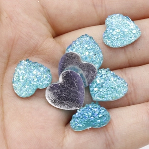 Macro-opname van 12mm hartvormige hars glitterstenen in blauw en paars op een palm