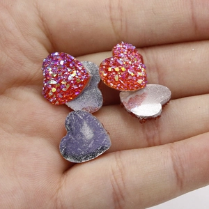 Macro-opname van 12mm hartvormige harsbedeltjes met glitter en metallic afwerking in hand
