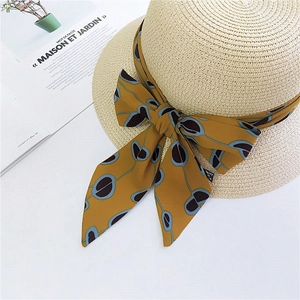 Straw sun hat with mustard yellow abstract pattern silk ribbon tied in a large bow