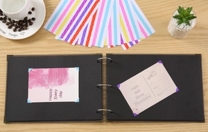 Détail de coins photos adhésifs fixant des cartes dans un album noir avec coins métalliques