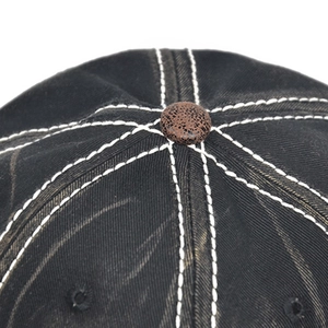Close-up of contrast stitching and top button on a vintage washed cotton baseball cap