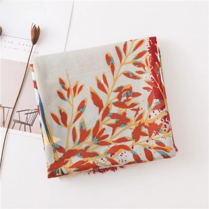 Detail view of light grey linen cotton scarf with orange floral prints and tassel fringe