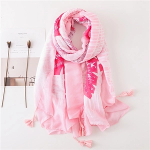 Détail d'un châle en coton rose avec motifs de feuilles blanches et glands à franges