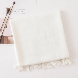Detailed view of cream cotton linen scarf with elegant tassel edges on a minimalist background