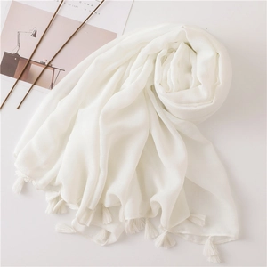 Close-up of white cotton linen scarf featuring delicate tassel fringe and soft texture