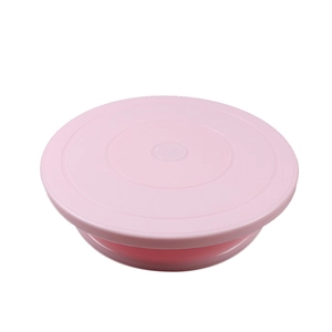Detail view of a pink plastic rotating cake turntable with circular textures on white background