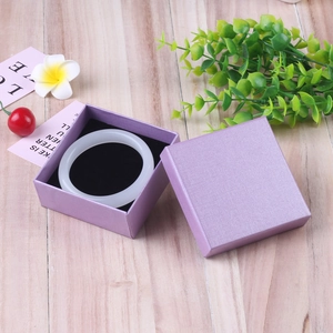Polished white jade bracelet in a premium purple textured gift box on a wooden background