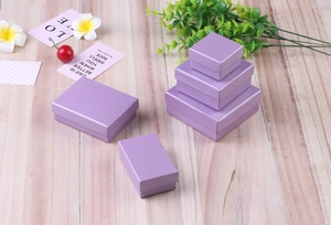 Purple textured jewelry gift boxes in various sizes displayed on a light wooden surface