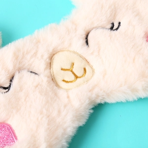 Detail of plush alpaca eye mask with embroidered eyelashes and pink sequins