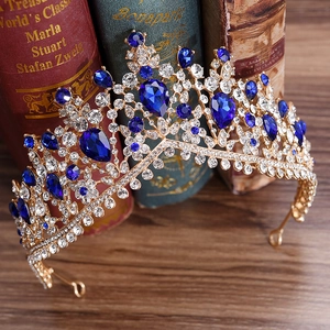 Macro detail of a golden bridal tiara featuring clear and blue rhinestones on vintage books