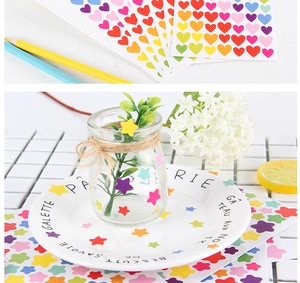 Detail of colorful heart and star stickers applied on a glass bottle in a bright setting