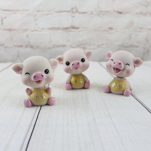 Trois figurines de cochons roses en résine avec des bavoirs jaunes porte-bonheur