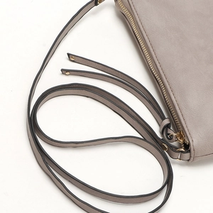 Close-up of beige leather envelope clutch with metal zipper and strap hardware detail