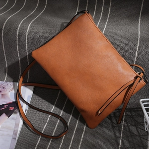 Close-up of a light brown leather envelope bag on a stylish striped textile background