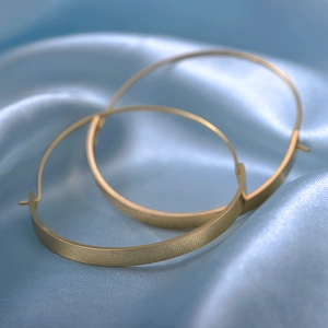 Chic gold-tone minimalist geometric semi-circle hoop earrings on silk background