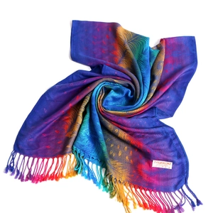 Macro shot of rainbow gradient pashmina shawl with peacock feather pattern and fringe