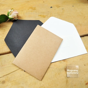Angled view of mini kraft paper envelopes in black white and brown on wood background