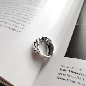 Close-up of a silver Cuban link chain ring displayed on a minimalist fashion magazine