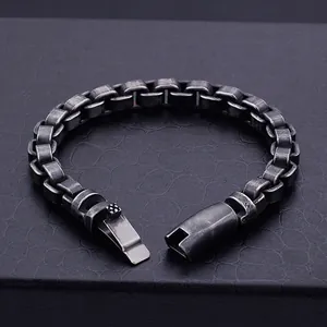 Vue macro d'un bracelet gourmette rétro en acier inoxydable vieilli sur fond de cuir noir