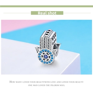 Macro detail of 925 silver Hamsa hand charm with blue zircons and star-shaped cutouts