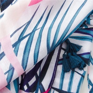 Détail d'un châle à imprimé tropical avec pompons bleus en tissu coton et lin léger