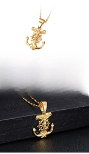 Detail of gold anchor cross pendant with jesus figure and steering wheel on steel chain