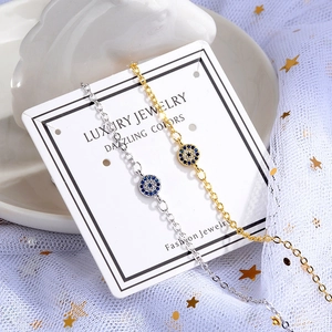 Elegant gold and silver Evil Eye bracelets with blue stones on a luxury display card
