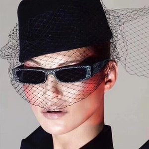 Detail einer quadratischen Sonnenbrille mit Silberkristall-Verzierung auf Model mit Schleier