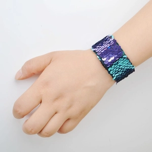 Detail shot of a two-tone purple and teal sequin snap bracelet worn on a wrist