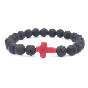 Macro shot of natural black lava stone beads with a vibrant red cross bead centerpiece