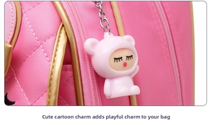 Detail of pink quilted school bag featuring a cute cartoon pendant and golden trim