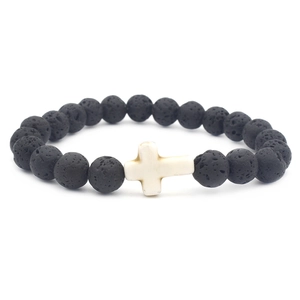 Black lava rock beaded bracelet with a white cross charm on a clean white background