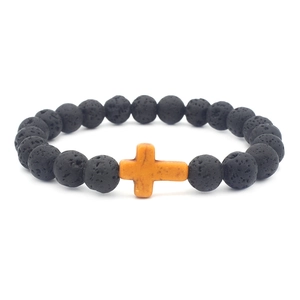 Detail view of black volcanic lava stone beads with a rustic yellow cross pendant charm