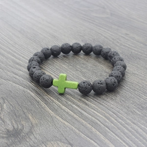 Macro view of volcanic lava stone beads featuring a green cross on a wooden texture
