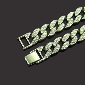 Macro shot of gold cuban link bracelet with sparkling rhinestones on dark background