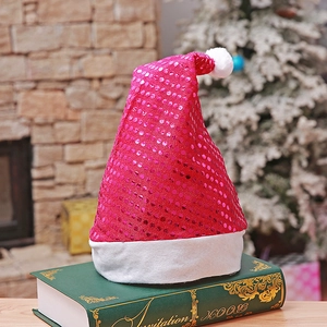 Detail of red sequined Christmas hat with white plush trim resting on a green book