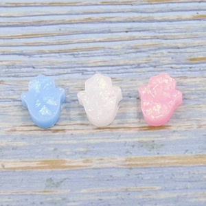 Close-up of blue, white, and pink Hamsa opal beads with iridescent glitter texture