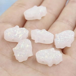 Close-up of iridescent white Opal Hamsa hand beads with small holes held in a palm