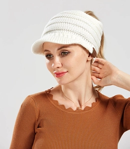 Close-up of knit ponytail beanie featuring soft cream texture and C.C leather patch